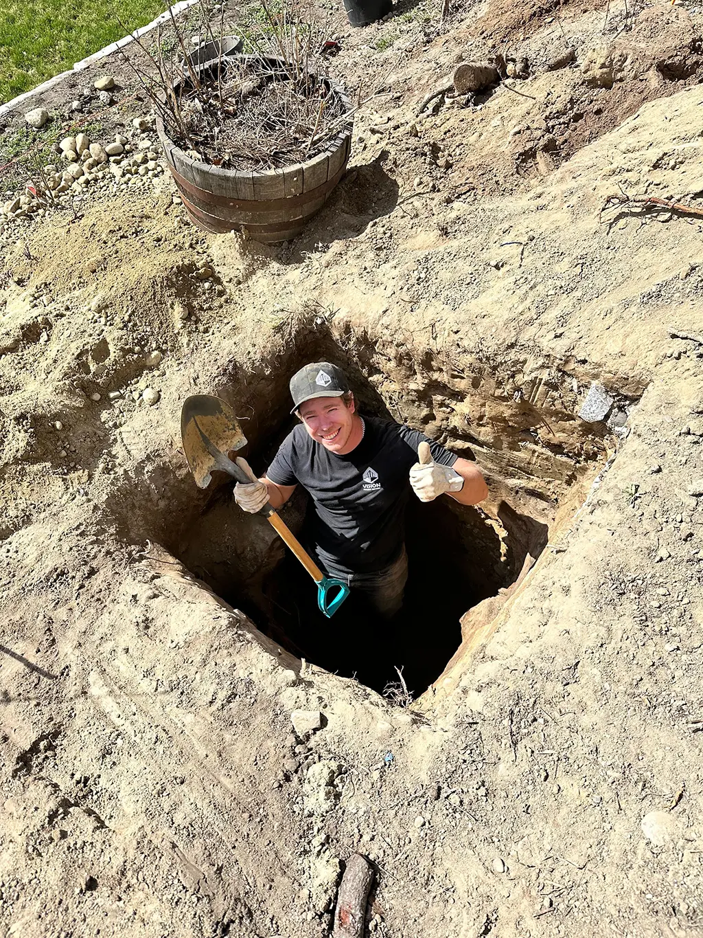 worker digging a hole, smiling, and giving a thumbs up